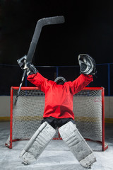Goalie standing elated with arms raised up above his head