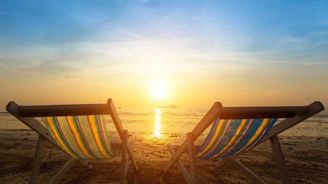 Two sunbeds on the sea beach during sunset.