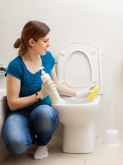 Young housewife cleaning toilet bowl
