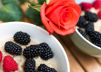 Romantic breakfast with berry cereals and rose