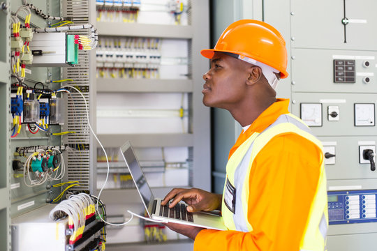 african industrial electrician working in control room