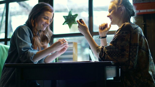 Girlfriends sitting in the cafe and talking about lipstick
