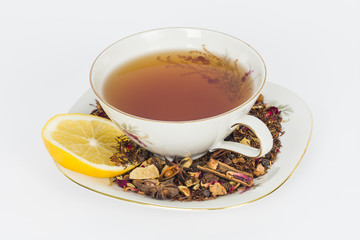 Cup of tea with loose rooibos tea leaves and slice of lemon