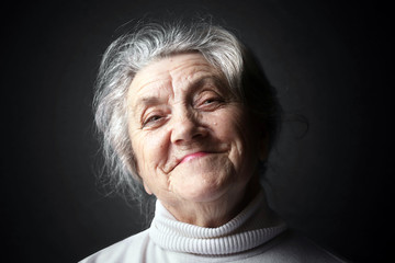 Happy granny portrait on a dark background 