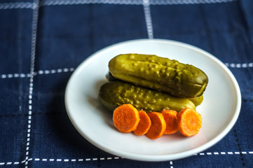 Pickled cucumbers and carrots cut. Looks delicious. Dietary food. Blue background.