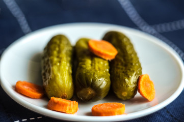 Pickled cucumbers and carrots cut. Looks delicious. Dietary food. Blue background.