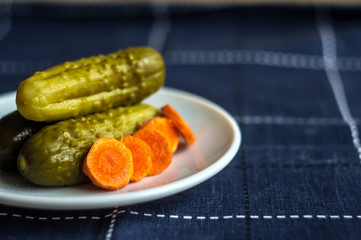 Pickled cucumbers and carrots cut. Looks delicious. Dietary food. Blue background.