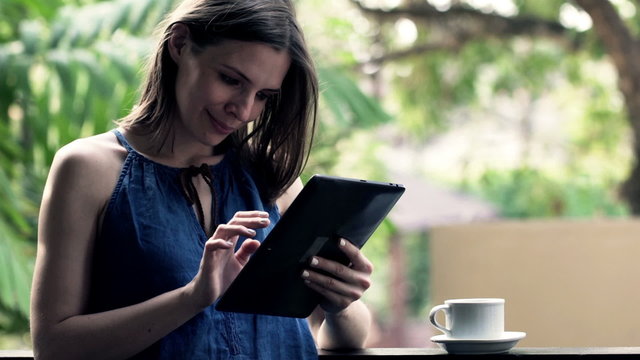Portrait of happy, beautiful woman with tablet compute standing on balcony
