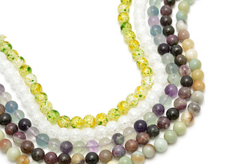 Strings of gems for making jewellery on white background