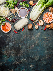 Asian cooking ingredients: rice noodles, pok choy , sauces, shrimps, chili and Shiitake mushrooms on dark background, top view, place for text. Asian food concept: Chinese or Thai cuisine. © VICUSCHKA