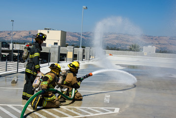 Naklejka premium Firefighters training for fire with water hose