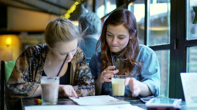 Girl sitting in the cafe and reading menu together
