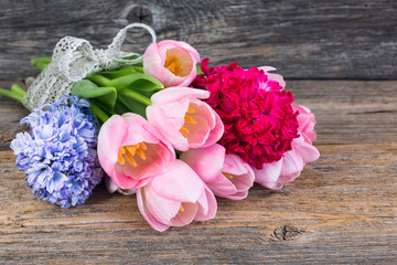 Bouquet of spring flowers decorated with ribbon on old wooden table. Soft focus 