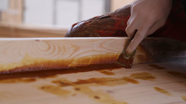 Carpenter blurs resin the spatula the seams of wooden boats at the shipyard
