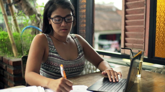 Overwhelmed, sad woman with documents and laptop sitting by table at cafe
