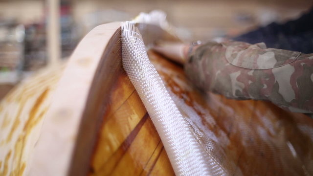 Construction of boats at the shipyard, gluing fiberglass on the side of the boat with resin
