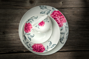 dining porcelain set of plates and one cup with floral ornament on wooden background, product photography