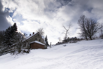 Snow covered house in a frosty mountains country in sunny winter day