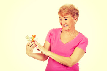 Smiling senior woman holding few tablets package