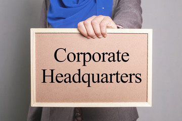 Businesswoman holding a softboard written Corporate Headquarters
