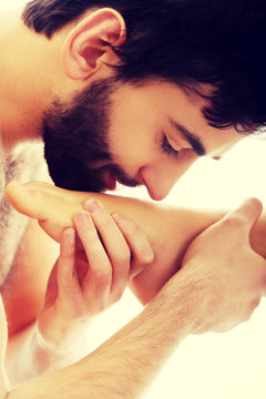 Handsome man kissing woman's feet.