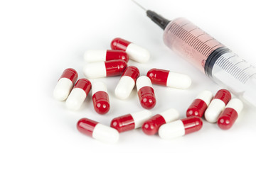 Hypodermic syringe and pills laying on a medical work surface