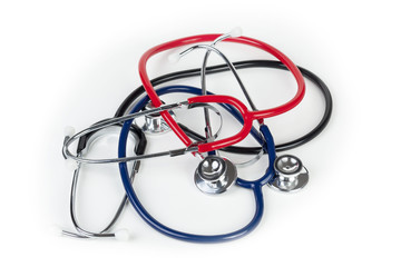 Red blue and black stethoscopes laying on medical worktop