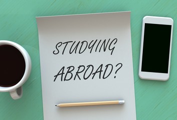 Studying Abroad, message on paper, smart phone and coffee on table