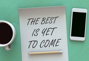 The Best is Yet to Come, message on paper, smart phone and coffee on table