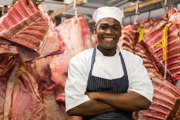 african butcher standing in meat storeroom