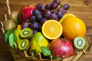 Mieszanka owoców egzotycznych w wiklinowym koszu na drewnianym tle