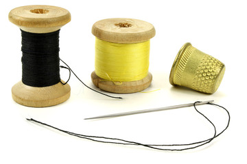 Old brass thimbles, coil with threads and a needle for sewing on a white background