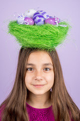 Little girl and nest with Easter eggs over her head