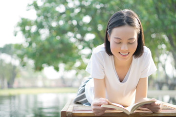 woman reading book in deck chair near swimming pool