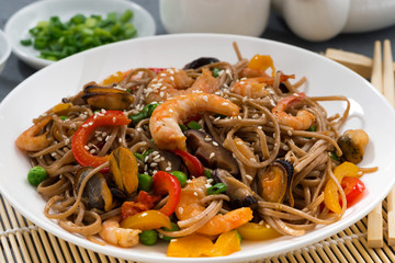 Asian buckwheat noodles with seafood and vegetables, closeup