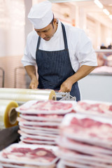 mid age butcher wrapping meat