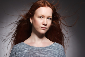 Portrait of a beautiful young woman with red long hair .