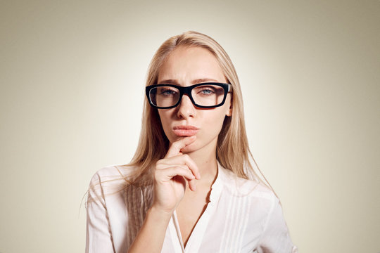 Healthy young thinking woman in glasses looking at camera on background with empty copy space