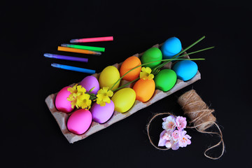Colored Easter eggs with colorful markers, rope and spring yellow flowers
