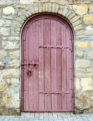 Ancient wooden door in old stone wall. 