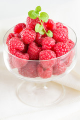 Frische Himbeeren in einer Glasschale mit einem Zweig Minze