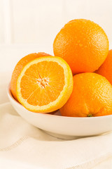 Apfelsinen liegen in einer Porzellan Schale auf einem Holzbrett