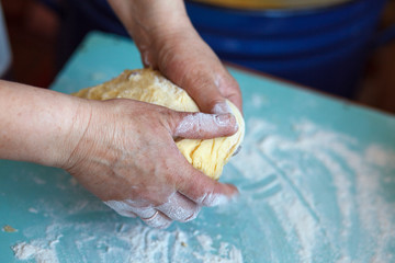 Woman's hands knead dough on a table