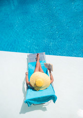 Woman relaxing at the swimming  pool reading a book