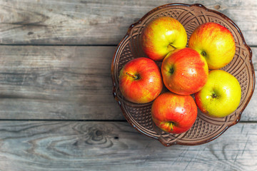 Fresh apples in a decorative vase for fruit on a wooden table.