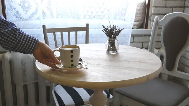 A man puts a cup of coffee on the table in slowmotion