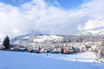 Ski slope with happy people at mountains with blue sky