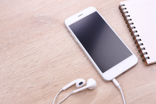 smartphone mockup with earphone and papre note on wooden backgro