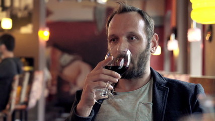 Young, happy man drinking wine and relaxing in cafe
 - Powered by Adobe