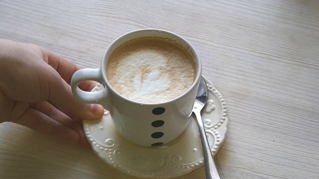 A man puts a cup of coffee on the table in slowmotion